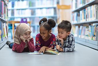 Three young children reading together in a library