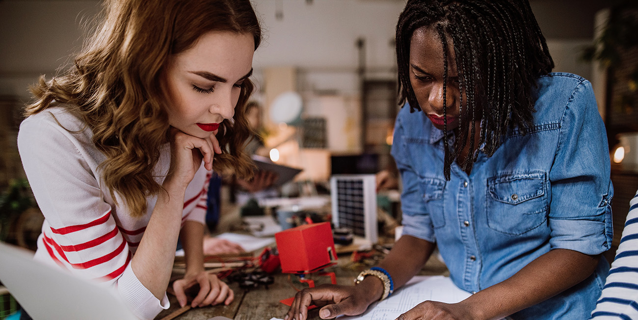 Image of young adult students working seriously together over laptops